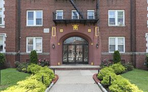 East Orange apartment for rent - the front door of a brick building with a walkway and grass