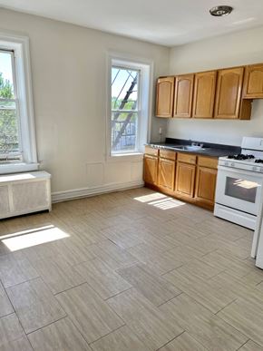 East Orange apartment for rent - an empty kitchen with wooden cabinets and a stove and a window