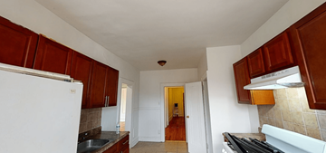 East Orange apartment for rent - a kitchen with white walls and wooden cabinets and a white refrigerator