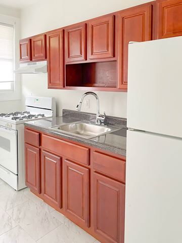 Irvington apartment for rent - a kitchen with brown cabinets and white appliances and a sink