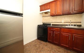 Irvington apartment for rent - A kitchen with brown cabinets and a black stove.