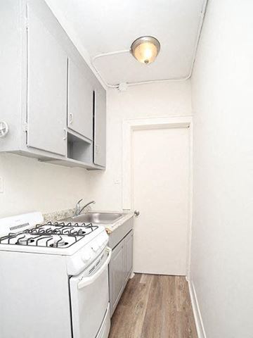 Irvington apartment for rent - A small white kitchen with a stove and a door.
