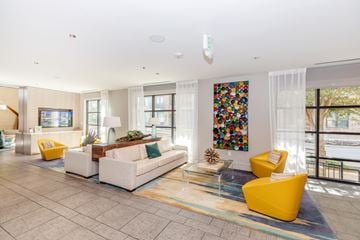 Dallas apartment for rent - A living room with a white couch, yellow armchair, and a colorful painting on the wall.