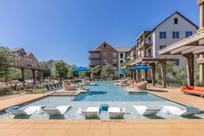 Dallas apartment for rent - A large outdoor swimming pool with loungers and umbrellas.