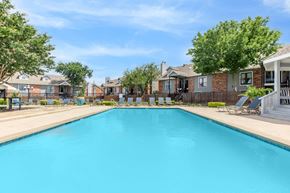 Waxahachie apartment for rent - A large swimming pool in a residential area with houses and trees around.