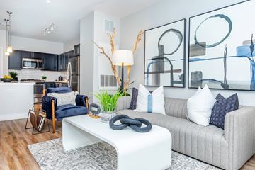 Norwalk apartment for rent - A modern living room with a grey couch, a white coffee table, and a large abstract painting on the wall.