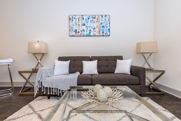 Fort Worth apartment for rent - A living room with a grey couch, a glass coffee table, and a painting on the wall.