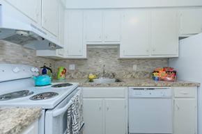 East Hartford apartment for rent - A kitchen with white cabinets and a stone backsplash.