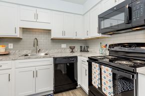 Waterbury apartment for rent - A kitchen with white cabinets and black appliances.