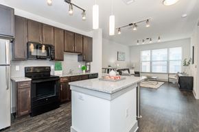 Fort Worth apartment for rent - A modern kitchen with dark brown cabinets and white appliances.