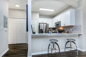 Jacksonville apartment for rent - A kitchen with white cabinets and a bar area with stools.