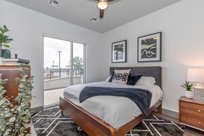The Colony apartment for rent - a bedroom with a large window and a bed with white sheets