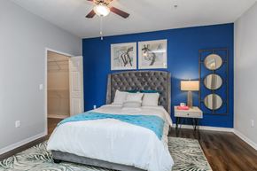 Jacksonville apartment for rent - A bedroom with a bed, a ceiling fan, and a nightstand with a lamp.