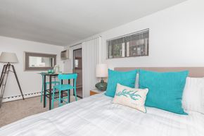 New London apartment for rent - A bedroom with a white bed and a blue chair.