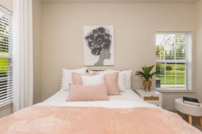 Dade City apartment for rent - A bedroom with a large bed and a painting of a tree on the wall.