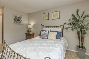 Apopka apartment for rent - A bedroom with a white bed and a plant.