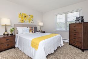 Naugatuck apartment for rent - A bedroom with a white bed and a yellow throw blanket.