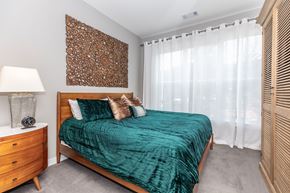 Bloomfield apartment for rent - A bedroom with a bed, nightstand, and a wooden wall art.
