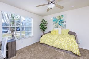 Panama City apartment for rent - A bedroom with a bed, a ceiling fan, and a window with blinds.