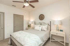 Jacksonville apartment for rent - A bedroom with a bed, a ceiling fan, and a nightstand with a lamp.