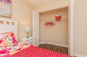 Jacksonville apartment for rent - A bedroom with a floral bedspread and a white nightstand with a blue lamp.