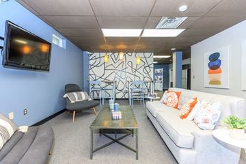 East Haven apartment for rent - A living room with a grey sofa, a grey armchair, a grey coffee table, and a television on the wall.
