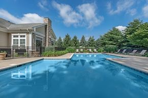 Manchester apartment for rent - A swimming pool in front of a house with trees in the background.