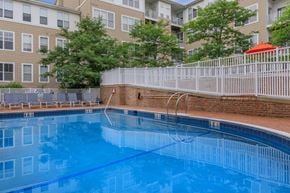 Stamford apartment for rent - A swimming pool in front of a building with a white fence around it.