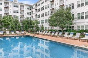 Norwalk apartment for rent - A pool with lounge chairs in front of a white building.