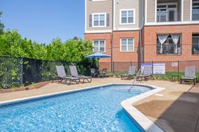 Meriden apartment for rent - A pool surrounded by chairs and a fence with a building in the background.