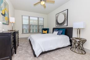Fort Worth apartment for rent - A bedroom with a large bed, a dresser, and a ceiling fan.