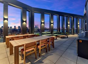 Jersey City apartment for rent - a communal dining table on a balcony with a view of the city