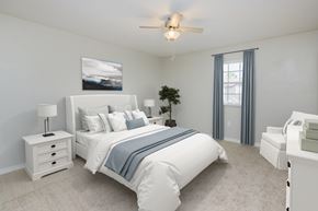 Lady Lake apartment for rent - A bedroom with a large bed, a ceiling fan, and a nightstand with a lamp.