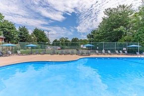 East Hartford apartment for rent - A large blue swimming pool surrounded by a fence and lounge chairs.