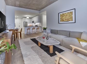 Jersey City apartment for rent - A modern living room with a grey sofa, wooden coffee table, and a large painting on the wall.