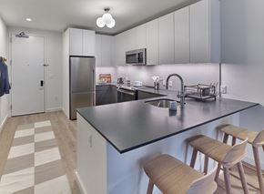 Jersey City apartment for rent - A kitchen with a black counter top and wooden bar stools.