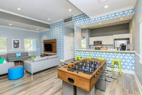 Jacksonville apartment for rent - A foosball table in the middle of a room with a couch and a kitchen area in the background.