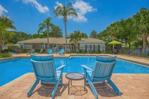 Riverview apartment for rent - A poolside setting with blue chairs and a table.