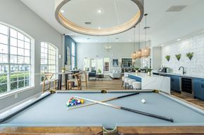 Jacksonville apartment for rent - A pool table is in the middle of a room with a kitchen and dining area.