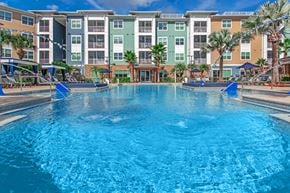Jacksonville apartment for rent - A large swimming pool in front of a multi-story apartment building.
