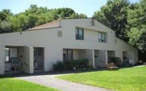 Waterbury apartment for rent - A white house with a brown roof and a green lawn in front.