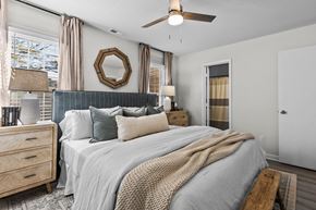 Wake Forest apartment for rent - A bedroom with a large bed, a ceiling fan, and a mirror on the wall at West Oak Apartments, Wake Forest, NC 27587