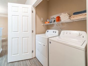 A white washer and dryer in a laundry room with a closet