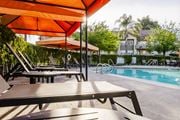 Moreno Valley apartment for rent - A poolside area with sun loungers and an orange umbrella. at Legends at Rancho Belago, Moreno Valley