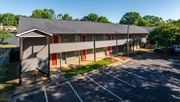 Kannapolis apartment for rent - a building with red doors and a parking lot at Ashford Place Apartments, Kannapolis, NC 28081