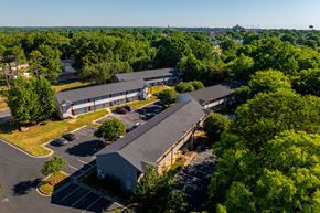 Kannapolis apartment for rent - a view from above of a building with a parking lot and trees at Ashford Place Apartments, Kannapolis, NC 28081