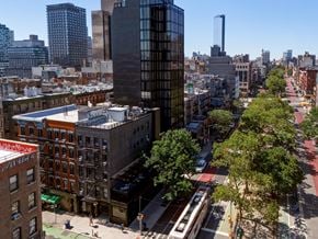 New York apartment for rent - A city street with a bus and buildings on either side.