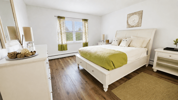 Norwich apartment for rent - A white bedroom with a bed, nightstand, and a dresser with a mirror.