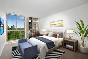 Laurel apartment for rent - A bedroom with a large bed and a large window overlooking a forest.