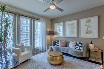 A living room with a ceiling fan and large windows